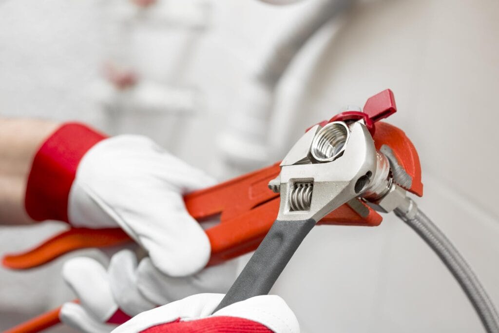 Plumber holding pipe wrenches for an emergency repair in Firestone