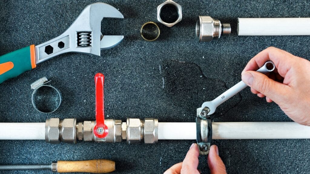 Plumber repairing a pipe valve with an adjustable wrench in Firestone