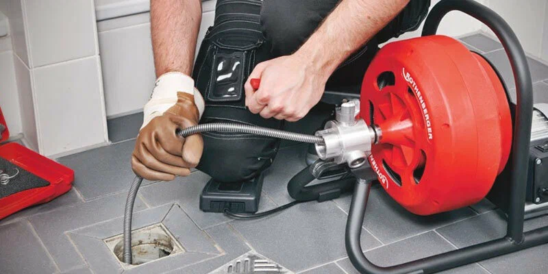 Plumber using a drain-cleaning machine in Firestone