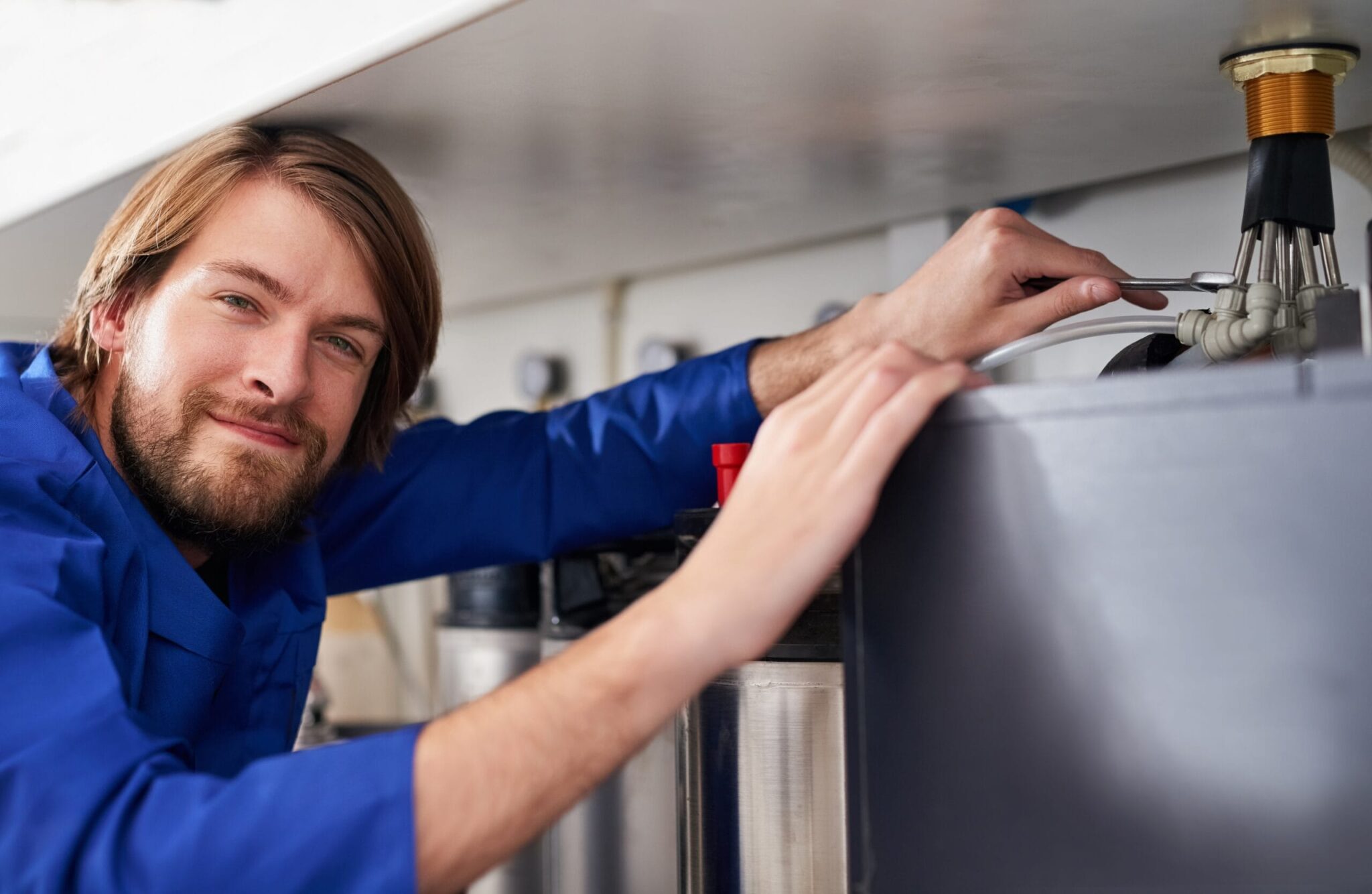 Technician servicing a residential water heater tank in Firestone