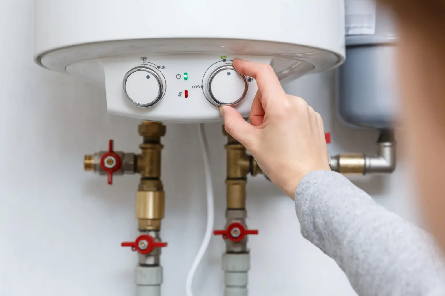 Homeowner adjusting the temperature controls on a water heater in Firestone